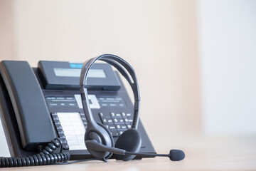 Communication support, call center and customer service help desk. VOIP headset on telephone keyboard.