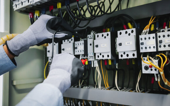 Electrical engineers test electrical installations and wiring on protective relays, measuring them with a multimeter.