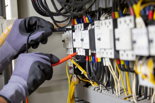 Electrician engineer tests electrical installations and wires on relay protection system. Adjustment of scheme of automation and control of electrical equipment.