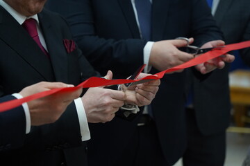 People in business suits cut the red ribbon at the opening
