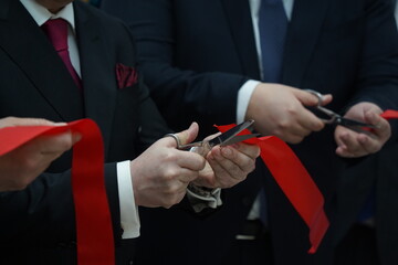 People in business suits cut the red ribbon at the opening