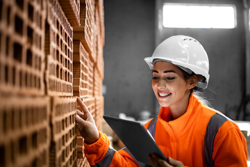 Industrial female worker checking quality of bricks for construction industry.