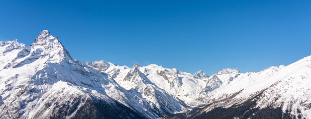 Obraz premium Panoramic view of winter snowy mountains in Caucasus region in Russia with blue sky