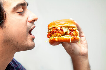 Eastern man looking at crispy chicken burger and is about to eat it.