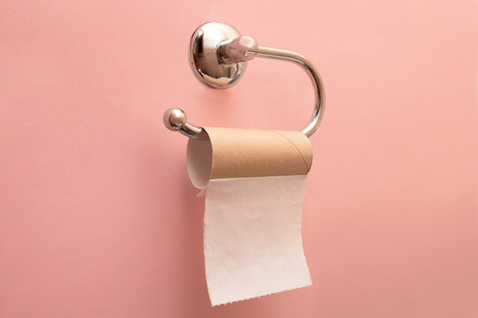 Empty toilet paper roll. The last sheet of toilet paper. Pink background. Emergency situation.