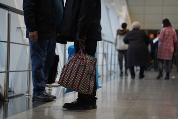 Fototapeta premium Almaty, Kazakhstan - 03.16.2022 : Passengers with luggage walk along the aisle to the airport building. Reflection in the glass.