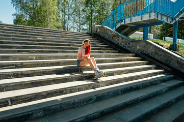 Woman in roller skates sits on steps.