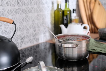 Woman in apron cooking delicious borscht soup on the hob