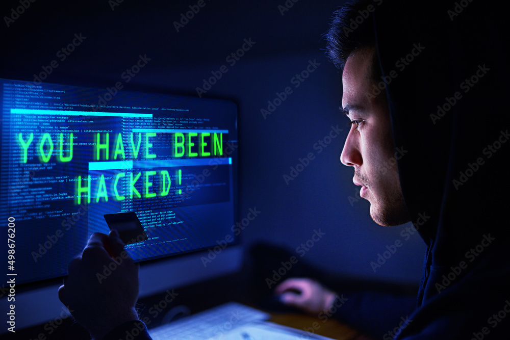 Poster your money is mine now. shot of a hooded computer hacker using a computer in the dark.