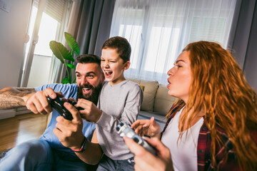 Playful family playing video games together in a living room.