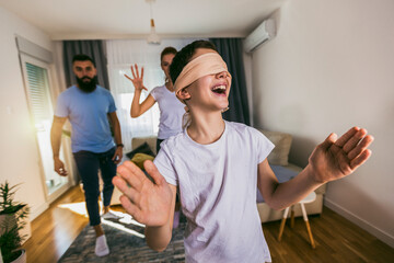 Family playing hide and seek at home, happy boy having fun with mom and dad.