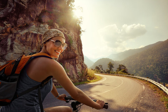 Woman tourist riding bike on mountain road