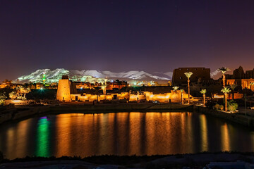 Night scene of Karnak Temple Complex in Luxor with a sacred lake and the ruined structure.