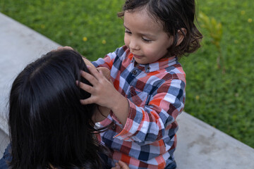 Mom and her Latin American son sitting on a bench showing their love with smiles and happiness....
