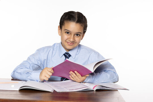 young girl of primary school sitting in classroom holding notebook isolated on white background