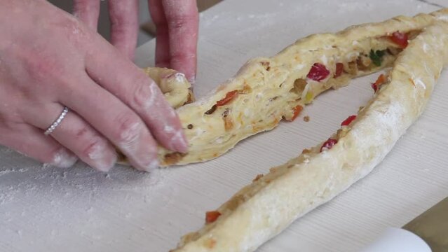 A woman prepares a cruffin with raisins and candied fruits. Rolls the dough cruffin. Tools and ingredients are laid out on the table.