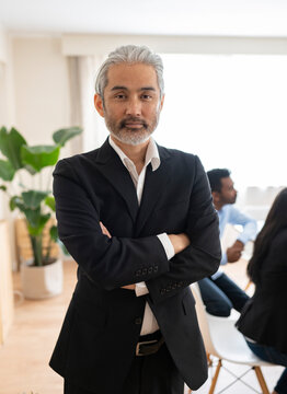 Handsome Asian Senior Man In Office With Arms Folded