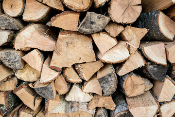 Background of stacked chopped wood logs. Pile of wood logs ready for winter. Wooden stumps, firewood stacked in heap