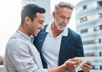 The best collaborating tool on the block. Shot of two businessmen using a digital tablet against an...