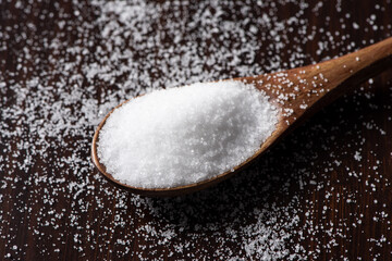 salt in a wooden spoon on table.