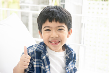 Portrait of happy boy showing thumbs up gesture, isolated over white background.