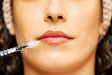 Crop woman with medical syringe against lips