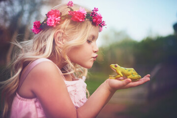 Will you turn into a prince if I kiss you. Shot of a cheerful little girl holding a frog and going...