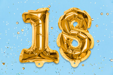The number of the balloon made of golden foil, the number eighteen on a blue background with sequins. Birthday greeting card with inscription 18. Numerical digit, Celebration event, template.