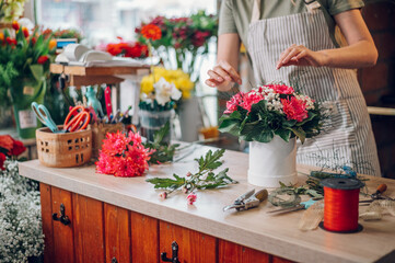 Florist woman creating flower arrangement in a round box