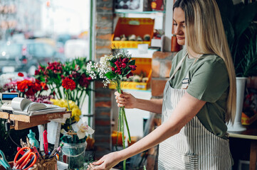 Female florist making a fresh flowers bouquet in a flower shop