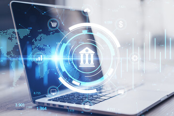 Close up of laptop on desktop with creative online banking hologram on blurry background....