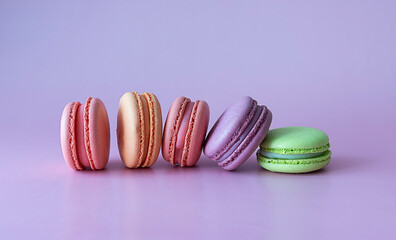 Pink, beige, lilac and green macaroons on a lilac background. A horizontal frame. Purple background