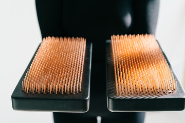 a sadhu board of their dark solid oak with copper nails, in the hands of a young girl on a white background. yoga practice standing on nails