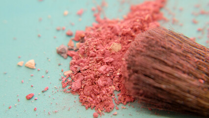 Closeup of the hair of brush head, covered with pink makeup powder, with a pile of pink cosmetic under the brush.