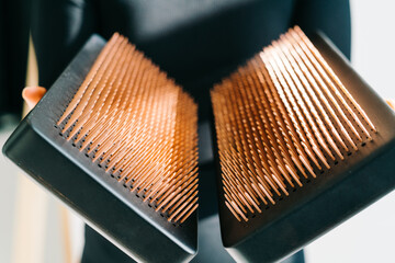 a sadhu board of their dark solid oak with copper nails, in the hands of a young girl on a white background. yoga practice standing on nails