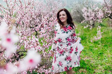 a woman in the garden of flowering peach trees in the spring