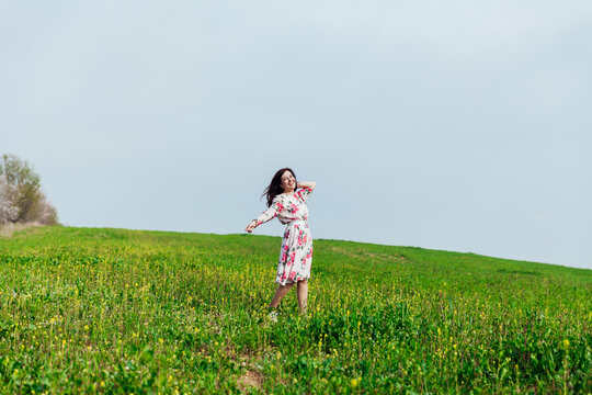 a woman walks in a blooming green field in spring