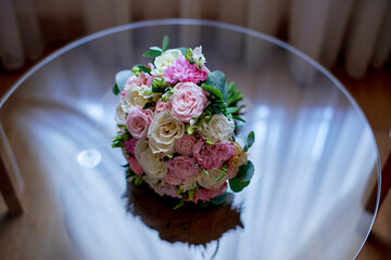 multi-colored wedding bouquet lies on a glass table reflection glitter rose eustoma white pink