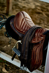 leather saddle for riding close-up straps on the fence stirrups