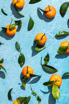Tropical tangerines with leaves on blue surface