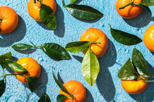 Crop of tropical tangerines with leaves on blue surface