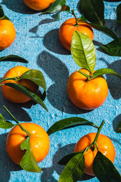 Crop of tropical tangerines with leaves on blue surface