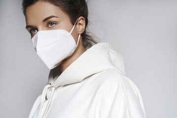 Young woman wearing white hoodie and ffp2 respirator mask