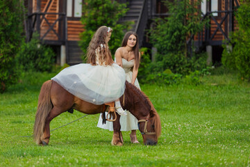 Obraz premium mother rides her daughter on a pony on a green lawn