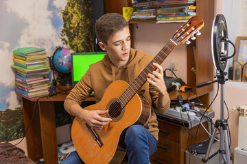 boy playing guitar sitting in his room