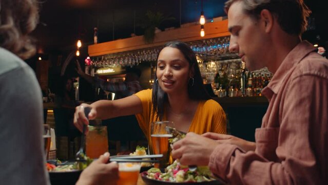 Diverse group of friends eating out at restaurant tasting food