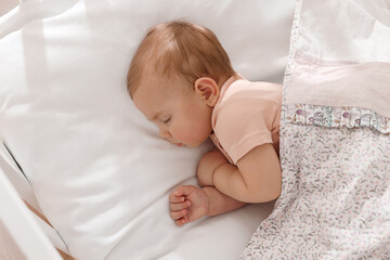 Cute little baby sleeping in soft crib, top view