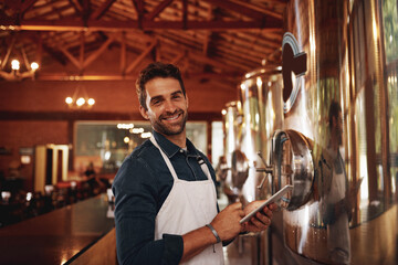 Im always happy when Im at work. Portrait of a cheerful young barman browsing on a digital tablet...