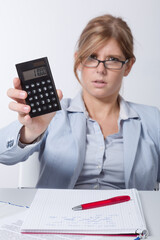 young business woman working with documents and a laptop at office desk is presenting a calculator