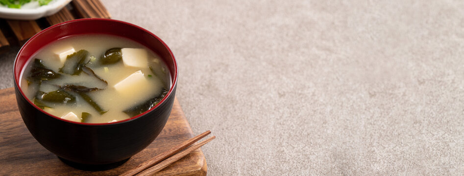 Delicious savory Japanese miso soup in a black bowl for eating.